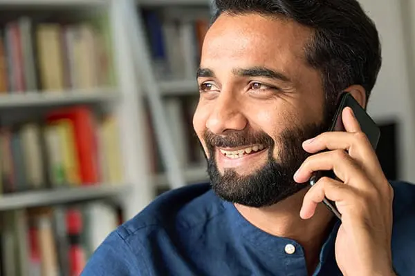 Happy smiling bearded successful eastern etthnic indian professional business man talking on cell phone, eastern businessman making mobile phone call by cellphone at work. Close up view.