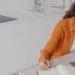 Tired spanish woman is taking notes at online conference. Teacher has remote lesson at home.