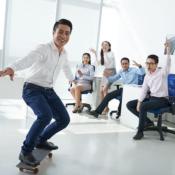Business people cheering when their colleague skateboarding in the office